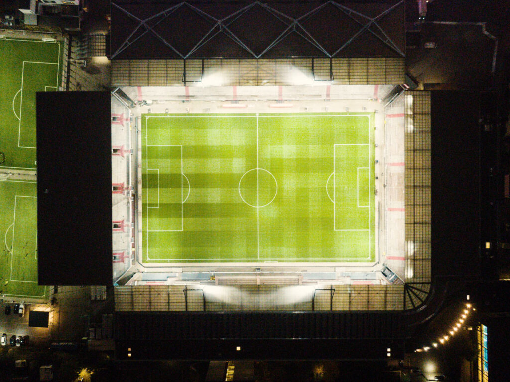 Drohnenansicht des St. Pauli Stadions mit den hell erleuchteten Tribünen.